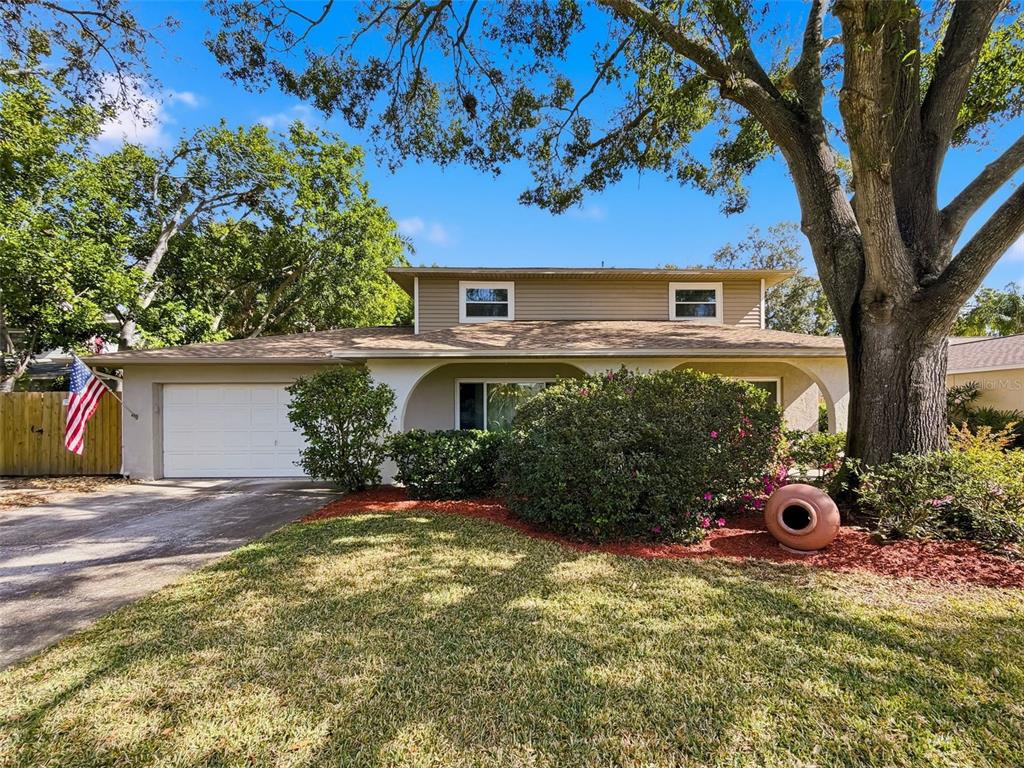 A two-story house with a tan exterior, a shingled roof, and a large front tree — 7923 SINGING COURT PLACE, TAMPA, FL
