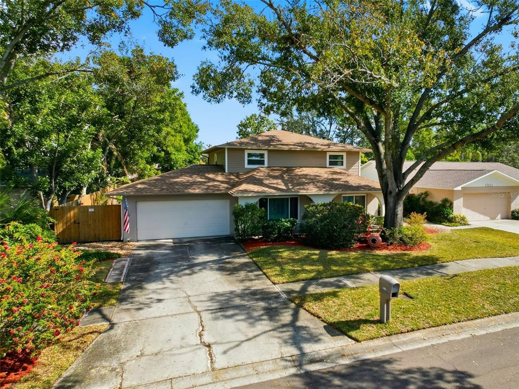 A two-story house with a tan exterior, a two-car garage, and a large front tree — 7923 SINGING COURT PLACE, TAMPA, FL