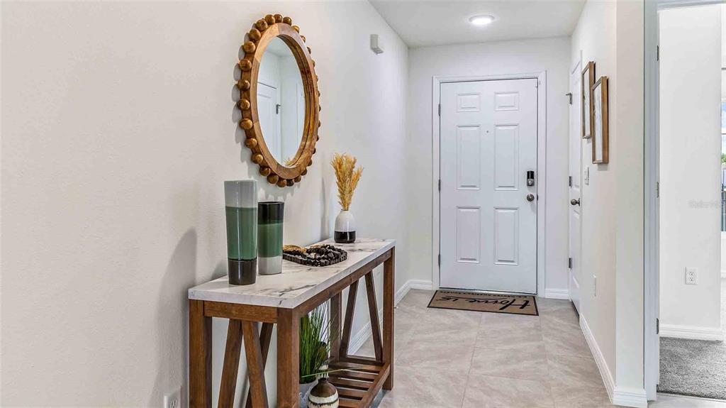 A bright entryway features a marble-topped console table, a round mirror, and tile flooring — 3514 HARVEST GARDENS LOOP, PLANT CITY, FL