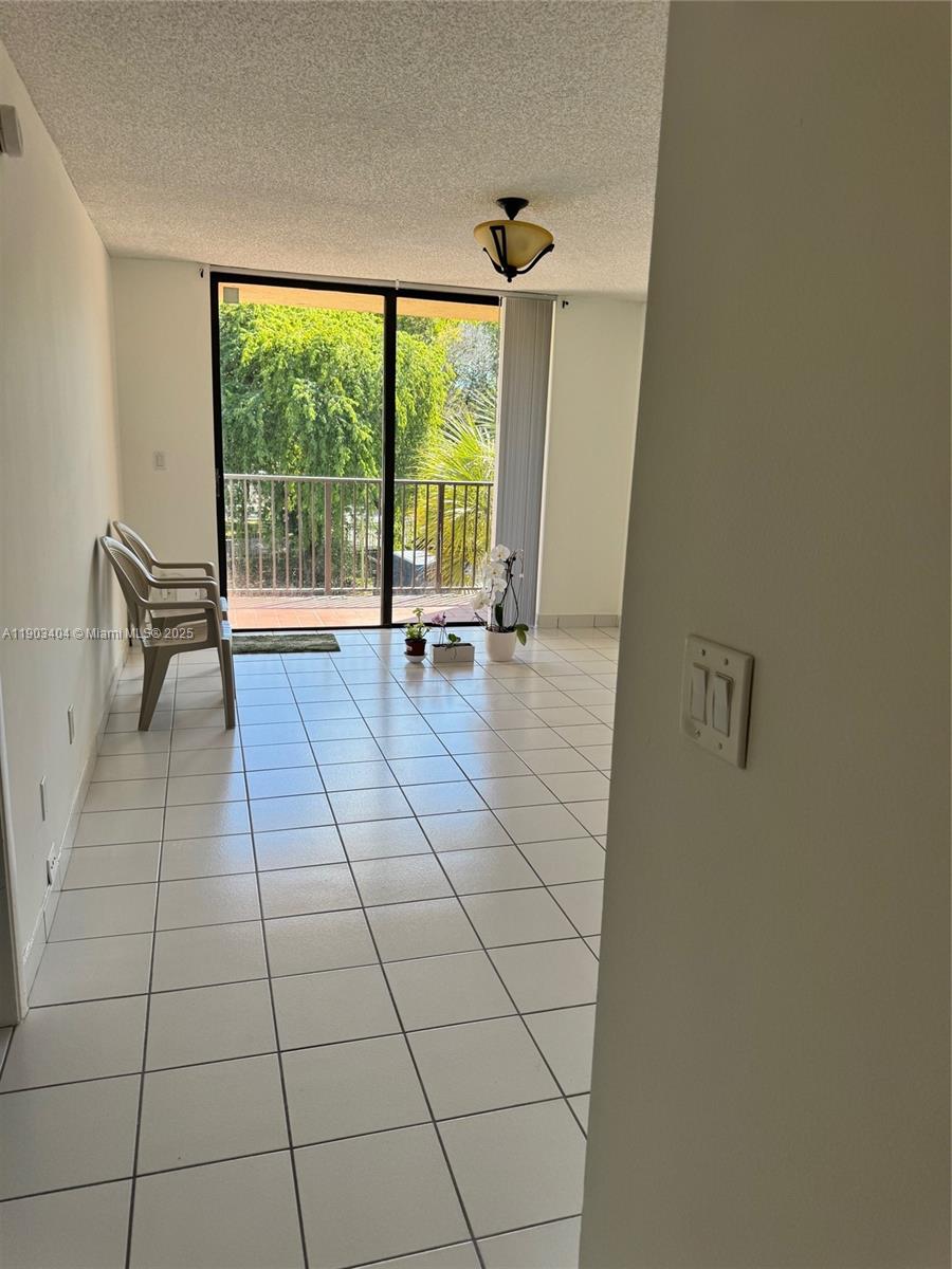 A room with white tile flooring features a sliding glass door leading to a balcony — 14401 N Kendall Dr # 303N, Miami FL 33186, MIAMI, FL
