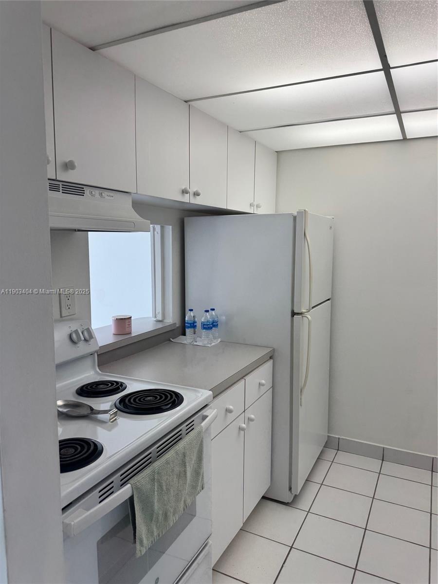 A small kitchen features white cabinets, white appliances, a gray countertop, and white tile flooring — 14401 N Kendall Dr # 303N, Miami FL 33186, MIAMI, FL