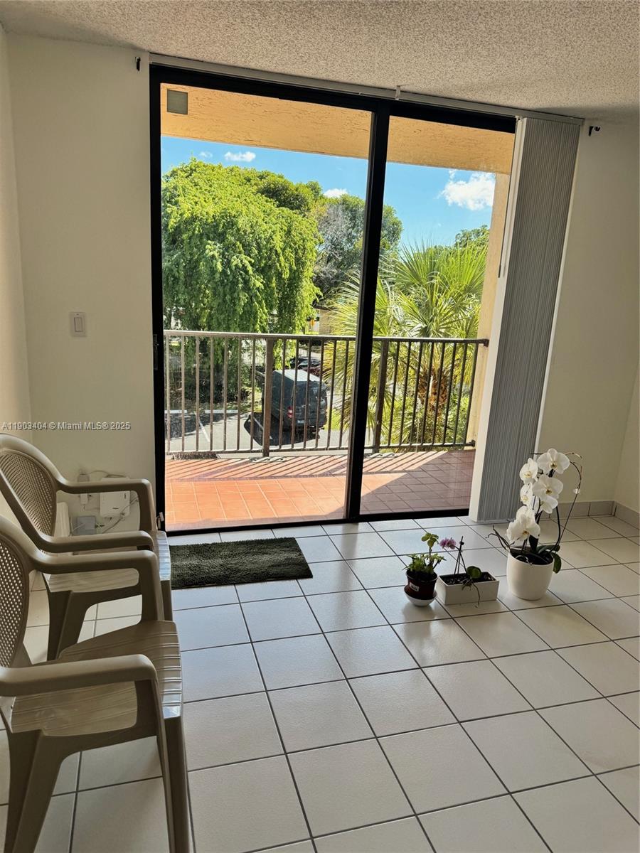 A tiled balcony features sliding glass doors, two plastic chairs, and several potted plants — 14401 N Kendall Dr # 303N, Miami FL 33186, MIAMI, FL