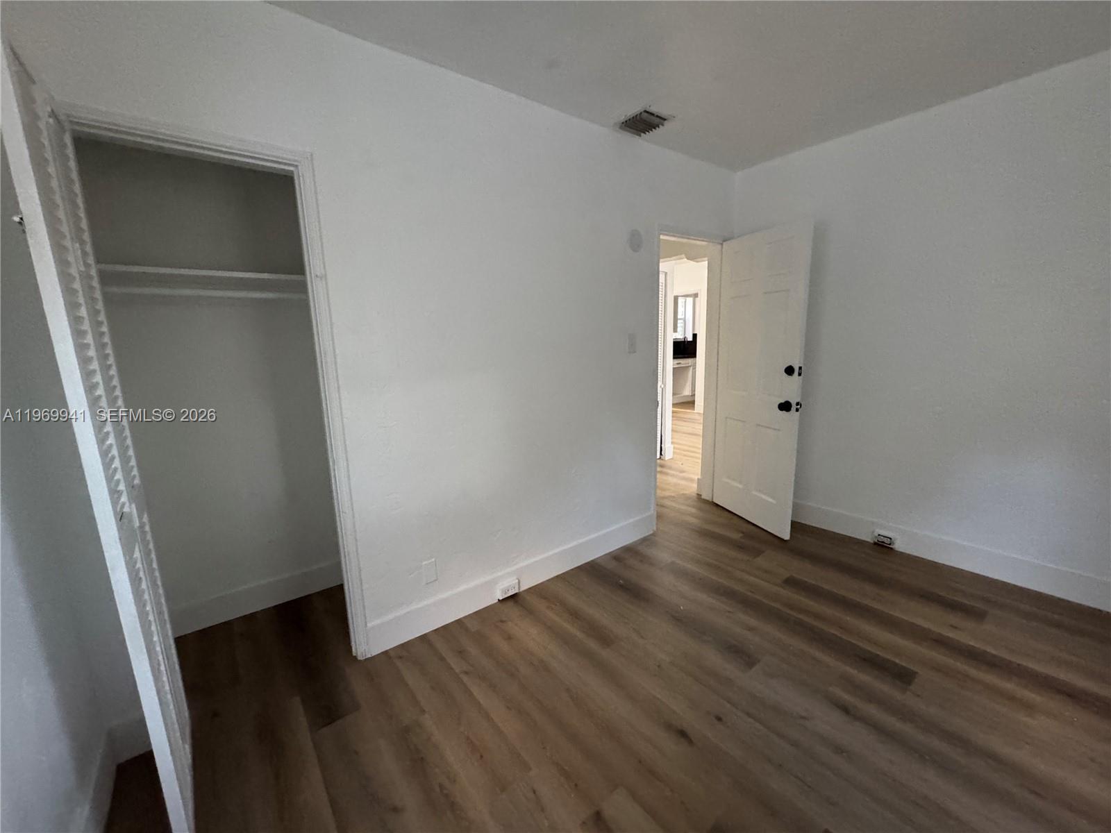 An empty room features white walls, wood-look flooring, a closet, and an open doorway — 748 NE 127th St, North Miami FL 33161, NORTH MIAMI, FL