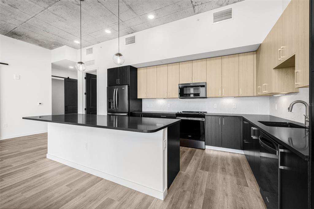 A modern kitchen features a black island, two-tone cabinetry, and a concrete ceiling — 221 MAIN STREET N UNIT PH 1612, ST PETERSBURG, FL