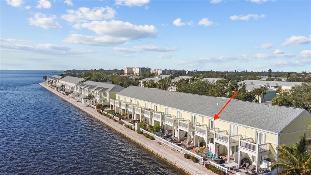 An aerial view shows a row of yellow waterfront townhouses with balconies along a bay — 5026 COQUINA KEY DRIVE SE UNIT 5026, ST PETERSBURG, FL