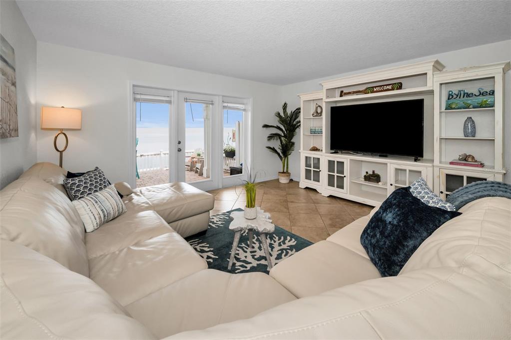 A living room features a white sectional sofa, a large media console, and patio doors — 5026 COQUINA KEY DRIVE SE UNIT 5026, ST PETERSBURG, FL
