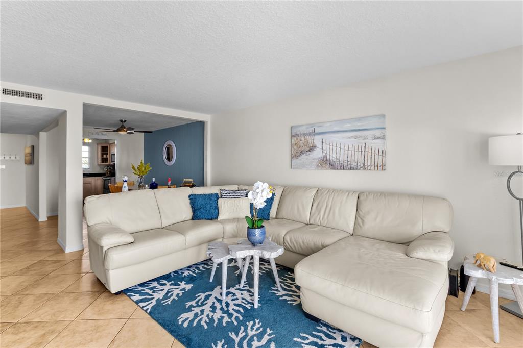 A living room features a large cream sectional sofa on a blue coral-patterned area rug — 5026 COQUINA KEY DRIVE SE UNIT 5026, ST PETERSBURG, FL