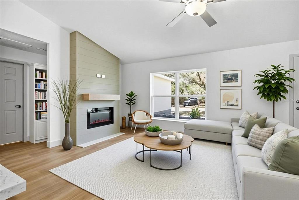 A living room features a fireplace with a shiplap surround, a sectional sofa, and wood flooring — 14095 SE 27TH COURT, SUMMERFIELD, FL