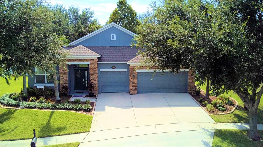 A single-story house with a blue facade, stone accents, and a three-car garage — 112 PECORRI COURT, AUBURNDALE, FL