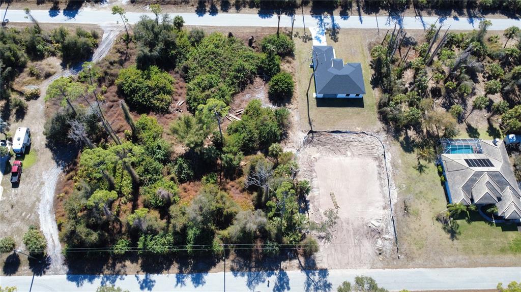 An aerial view shows a wooded lot with a cleared building pad and adjacent houses — 17213 FALLKIRK AVENUE, PORT CHARLOTTE, FL