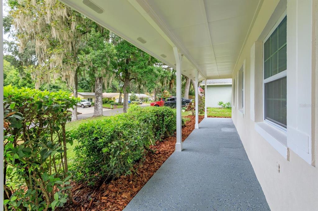 A covered porch with a gray speckled floor runs along the side of a house — 958 ORANGE AVENUE, OVIEDO, FL