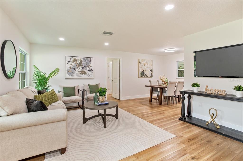 A living room and dining area feature light wood flooring, white walls, and modern decor — 958 ORANGE AVENUE, OVIEDO, FL