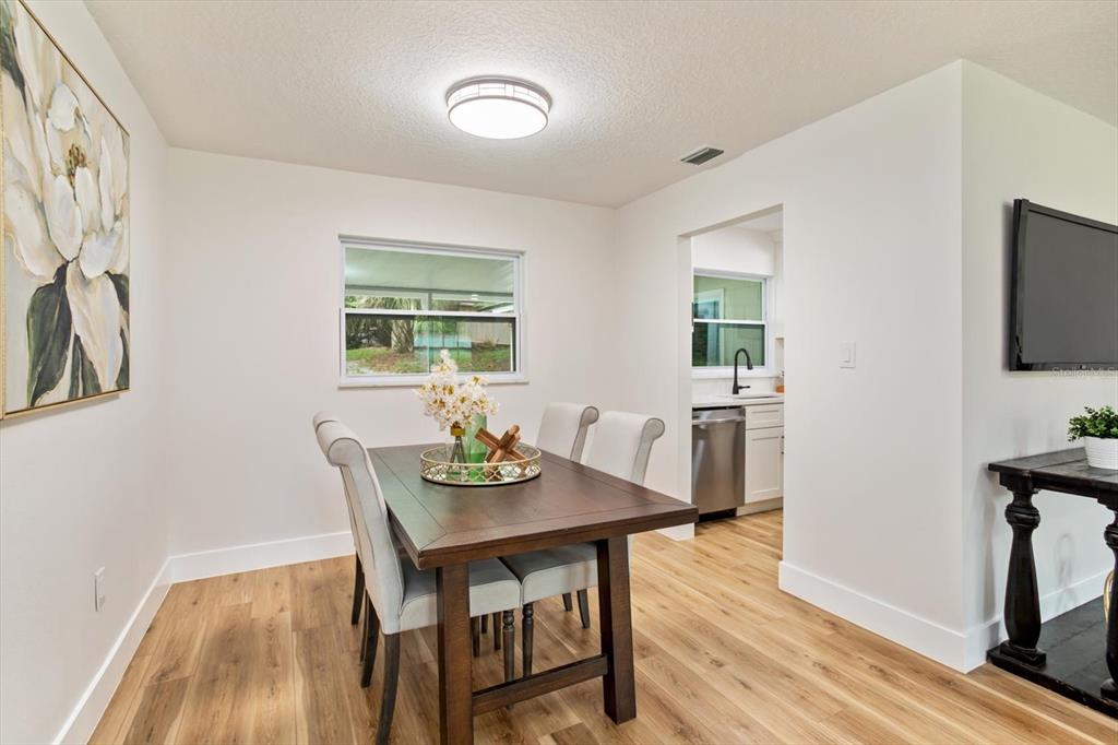 A dining room features a wooden table, upholstered chairs, light wood flooring, and a window — 958 ORANGE AVENUE, OVIEDO, FL