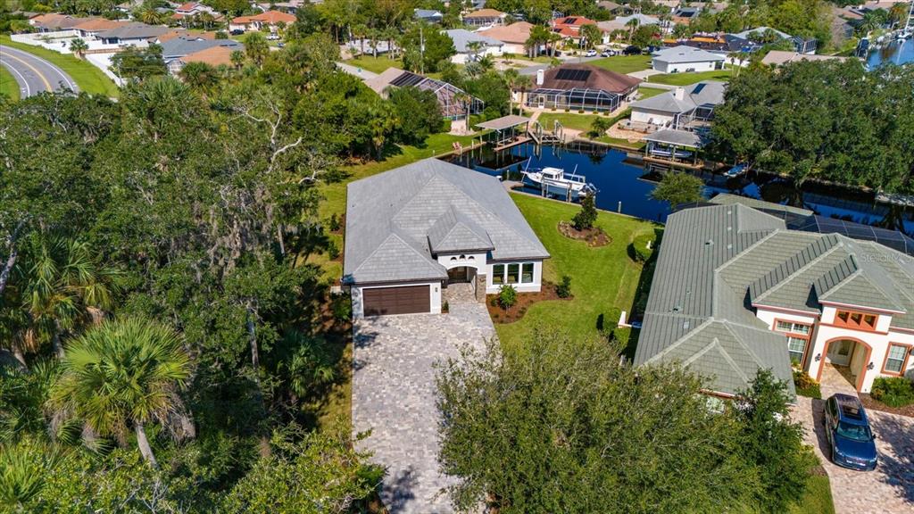 An aerial view shows a single-story house with a paved driveway and a private boat dock — 46 RIVERVIEW BEND N, PALM COAST, FL