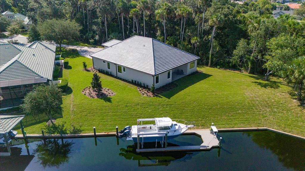 An aerial view shows a house with a gray roof, a lawn, and a boat dock — 46 RIVERVIEW BEND N, PALM COAST, FL
