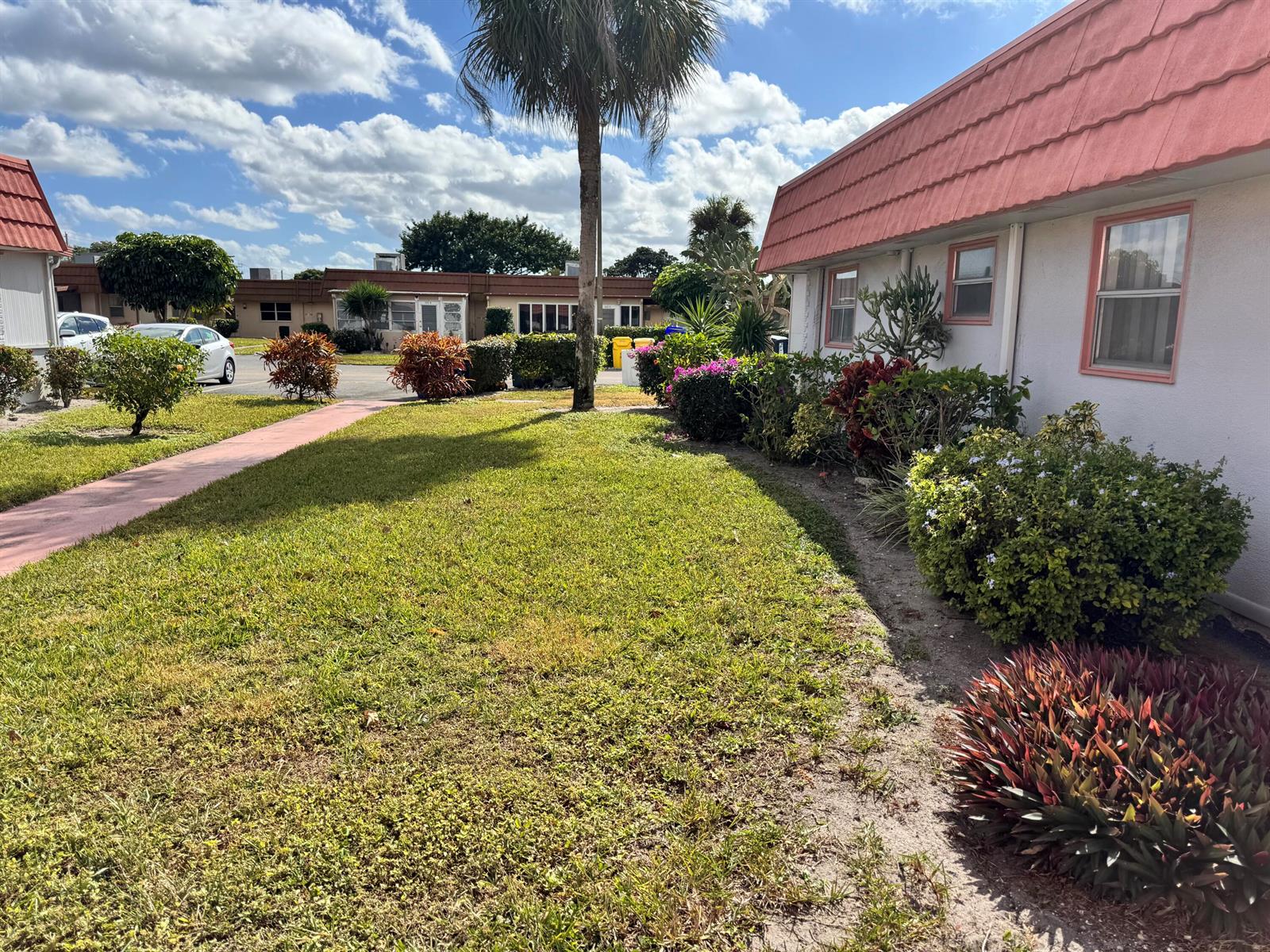 A grassy lawn sits in front of a single-story building with a red roof — 277 Seville L, Delray Beach FL 33446, DELRAY BEACH, FL
