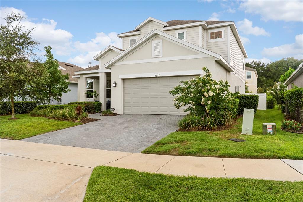 A two-story suburban house with a beige exterior, a paved driveway, and a two-car garage — 2527 NATOMA BOULEVARD, MOUNT DORA, FL