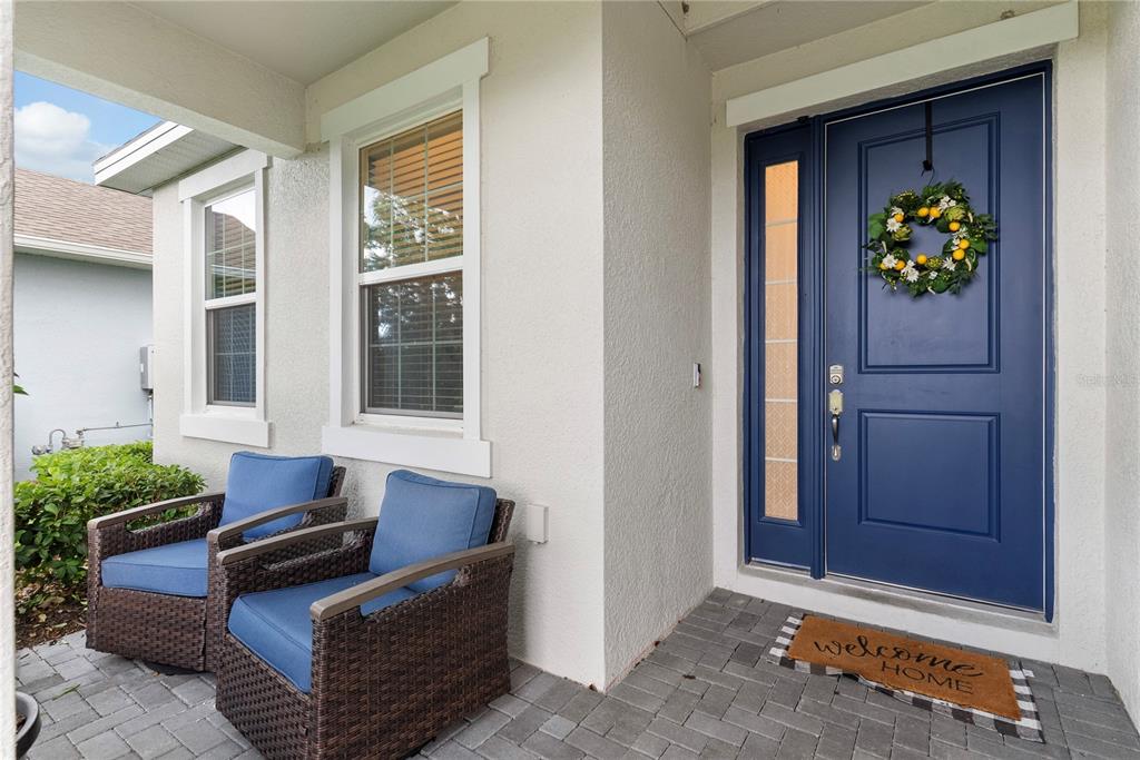A front porch features two wicker chairs with blue cushions and a blue front door — 2527 NATOMA BOULEVARD, MOUNT DORA, FL