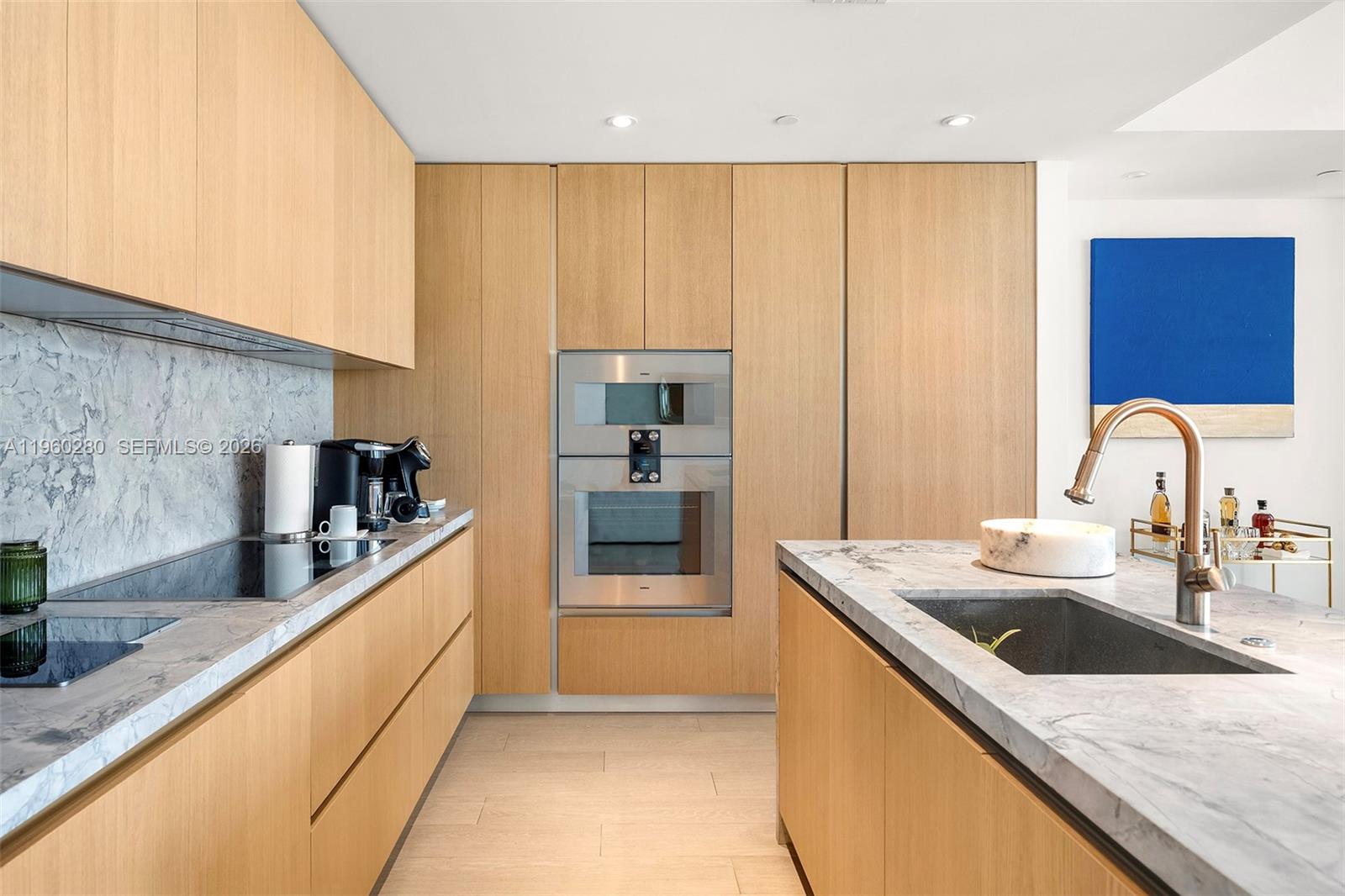 A modern living room features a large white sectional, wood-paneled wall, and floor-to-ceiling windows — 500 Alton # 2203, Miami Beach FL 33139, MIAMI BEACH, FL