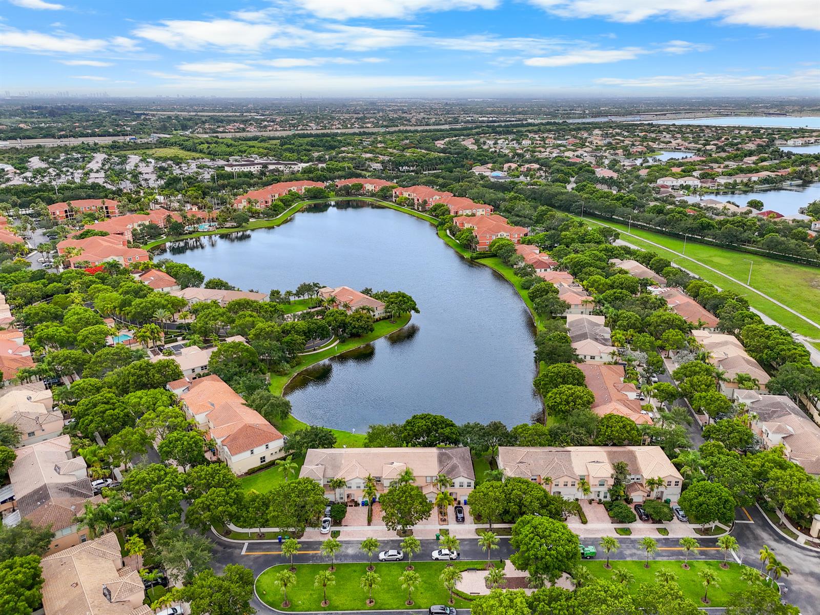 Aerial view of a residential complex with tile-roofed townhomes surrounding a central lake — 4735 SW 164th Avenue, Miramar FL 33027, MIRAMAR, FL
