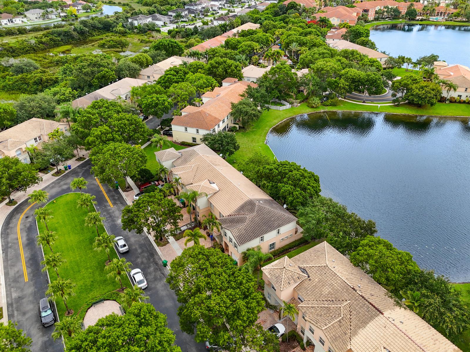 An aerial view shows residential townhomes situated along a lake and a winding canal — 4735 SW 164th Avenue, Miramar FL 33027, MIRAMAR, FL