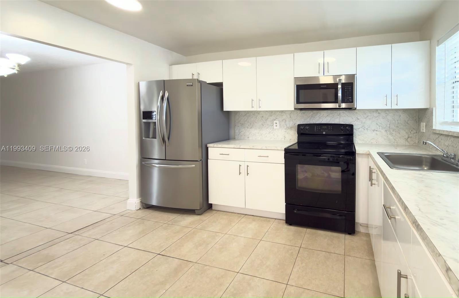 A kitchen features white cabinets, stainless steel appliances, a black stove, and marble-look countertops — 609 S State Road 7 # 1C, Margate FL 33068, MARGATE, FL