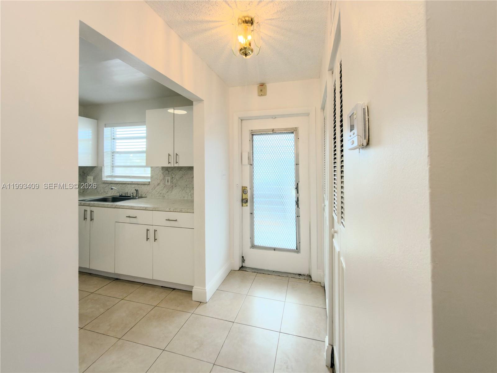 A white kitchen with tiled floors is visible through an opening next to an entryway — 609 S State Road 7 # 1C, Margate FL 33068, MARGATE, FL