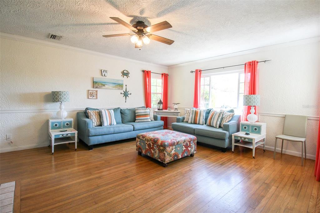 A living room features two blue sofas, a floral ottoman, and hardwood floors — 5812 7TH AVENUE NW, BRADENTON, FL