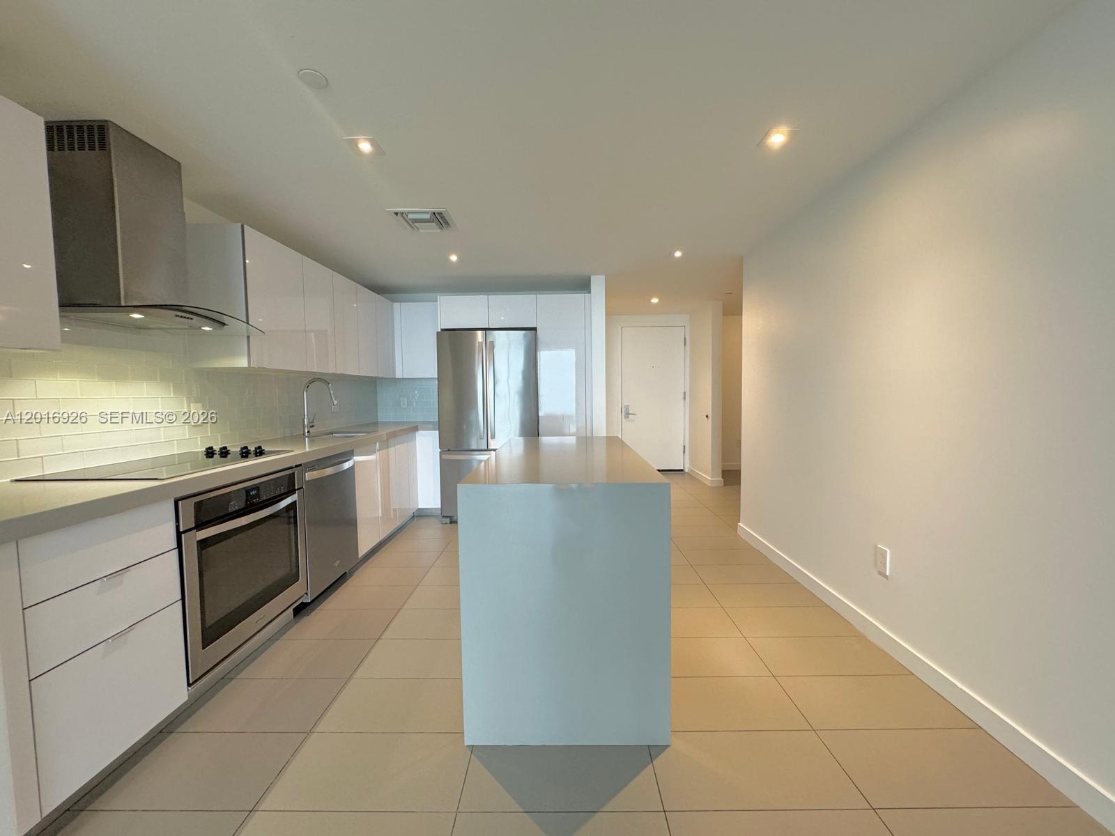 A modern kitchen features white glossy cabinets, stainless steel appliances, and a central island — 1600 NE 1st Ave # 3614, Miami FL 33132, MIAMI, FL