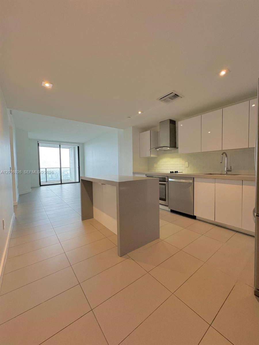 A modern kitchen features white cabinets, stainless steel appliances, and a gray island — 1600 NE 1st Ave # 3614, Miami FL 33132, MIAMI, FL