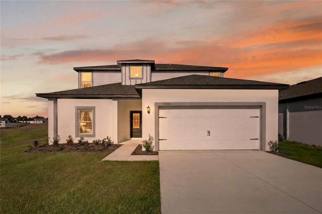 A two-story house with a white stucco exterior, a two-car garage, and a concrete driveway — 13430 LEAPING WATER WAY, ASTATULA, FL