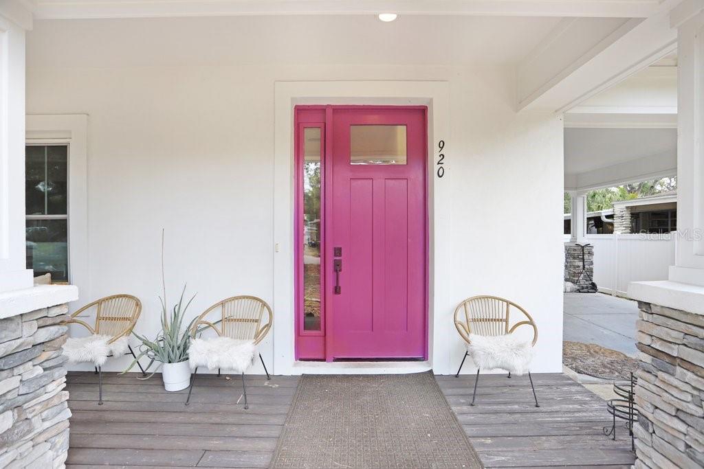 A front porch features a bright pink door, three rattan chairs, and stone pillar bases — 920 E SHADOWLAWN AVENUE, TAMPA, FL