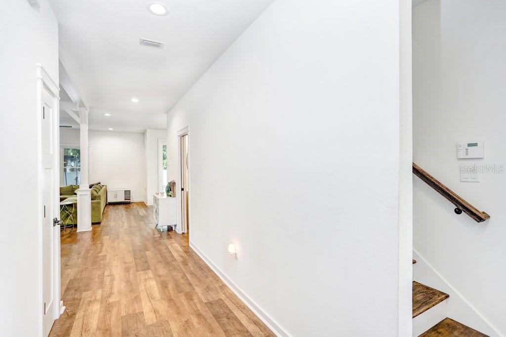 A hallway with wood-look flooring leads toward a living area with a green sofa — 920 E SHADOWLAWN AVENUE, TAMPA, FL