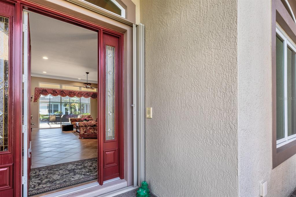 An open red front door reveals a view into a living room with tiled floors — 5530 CELEBRATION WAY, LEESBURG, FL