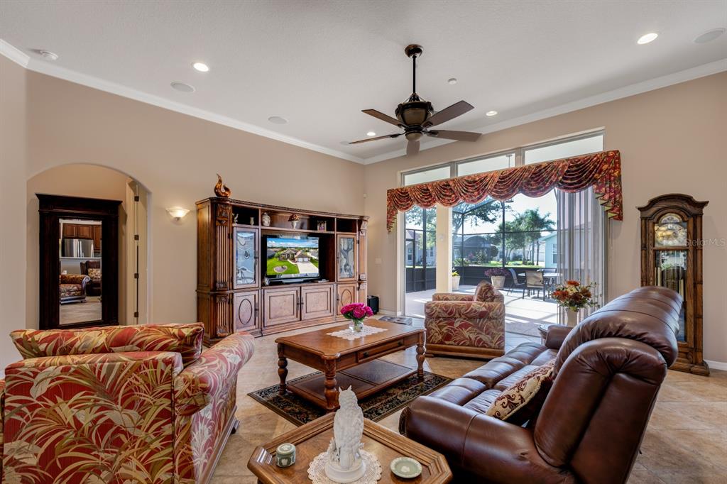 A living room features a large entertainment center, patterned furniture, and a sliding glass door — 5530 CELEBRATION WAY, LEESBURG, FL