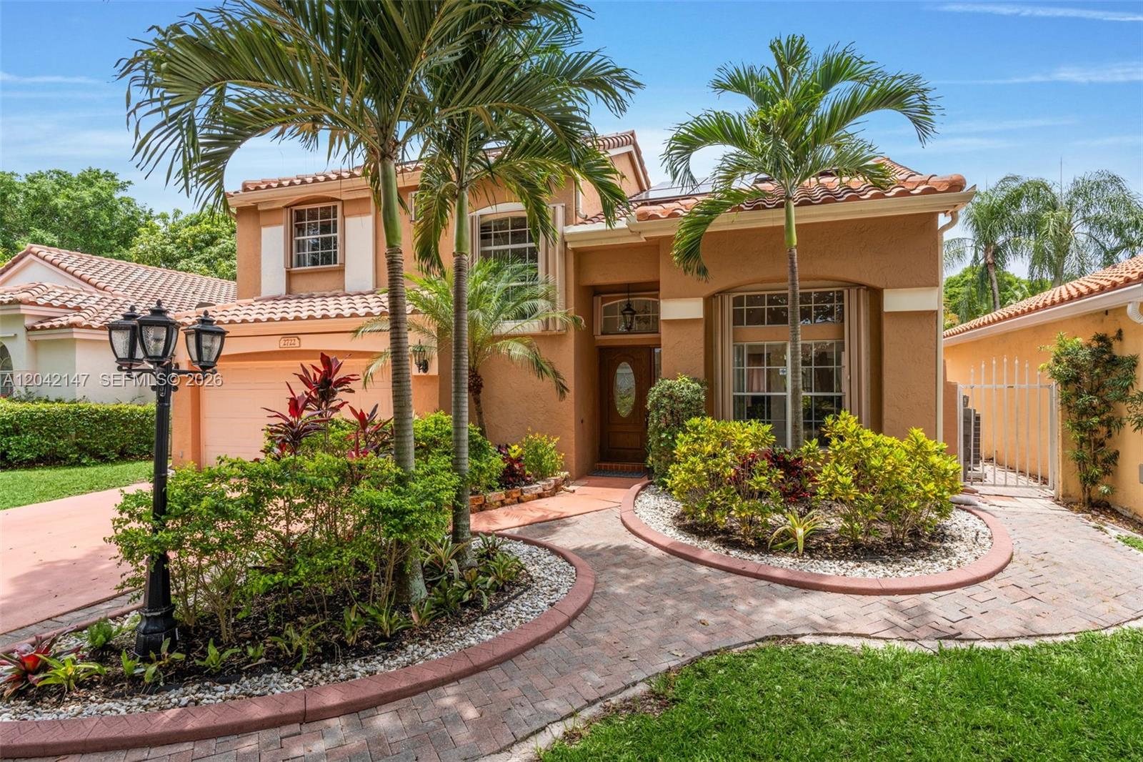 A two-story stucco house features a tiled roof, palm trees, and a brick walkway — 2722 Cayenne Ave, Cooper City FL 33026, COOPER CITY, FL