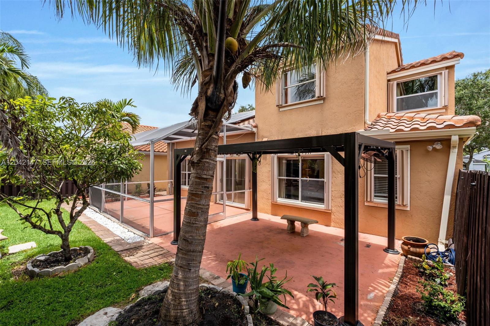 A backyard patio features a black metal pergola, a screened-in area, and a palm tree — 2722 Cayenne Ave, Cooper City FL 33026, COOPER CITY, FL