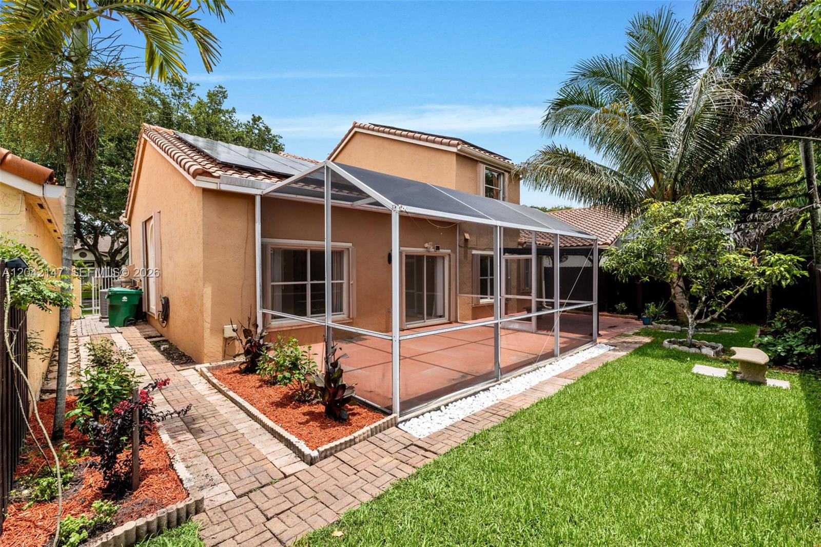 A tan house features a screened-in patio, a brick walkway, and a small grassy yard — 2722 Cayenne Ave, Cooper City FL 33026, COOPER CITY, FL