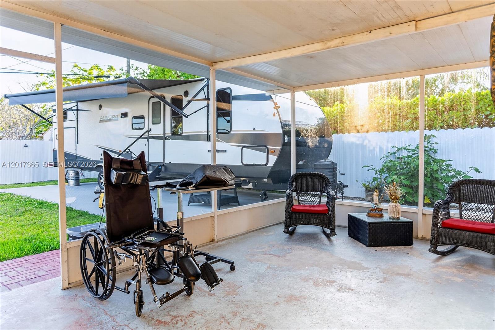 A screened-in patio features a wheelchair, two rocking chairs, and a view of a camper — 9760 Memorial Rd, Cutler Bay FL 33157, CUTLER BAY, FL