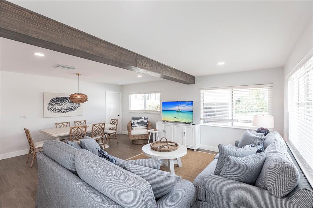 A living room and dining area feature light wood floors, a dark wooden ceiling beam — 6020 MIDNIGHT PASS ROAD UNIT 27, SARASOTA, FL