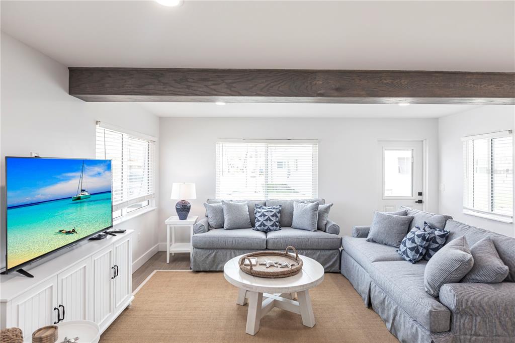 A living room features two gray sofas, a white coffee table, and a dark wood beam — 6020 MIDNIGHT PASS ROAD UNIT 27, SARASOTA, FL