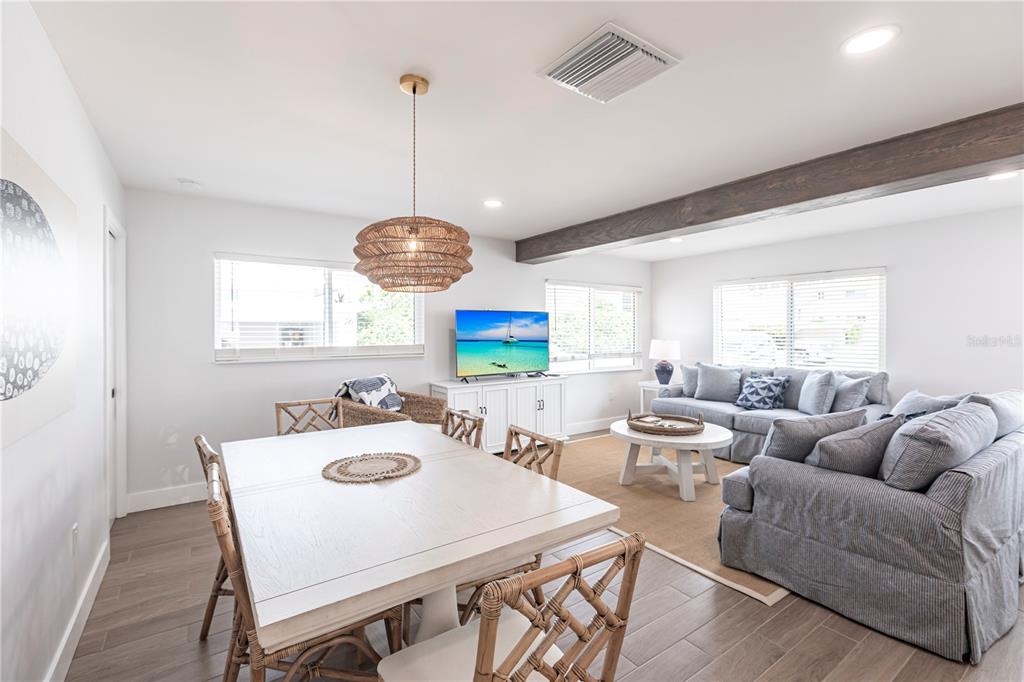 A dining area and living room feature light wood floors, white walls, and wicker furniture — 6020 MIDNIGHT PASS ROAD UNIT 27, SARASOTA, FL