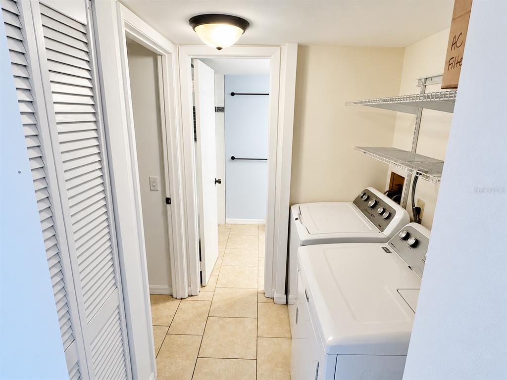 A laundry room features white appliances, wire shelving, and light-colored tile flooring — 1068 LOTUS PARKWAY UNIT 815, ALTAMONTE SPRINGS, FL