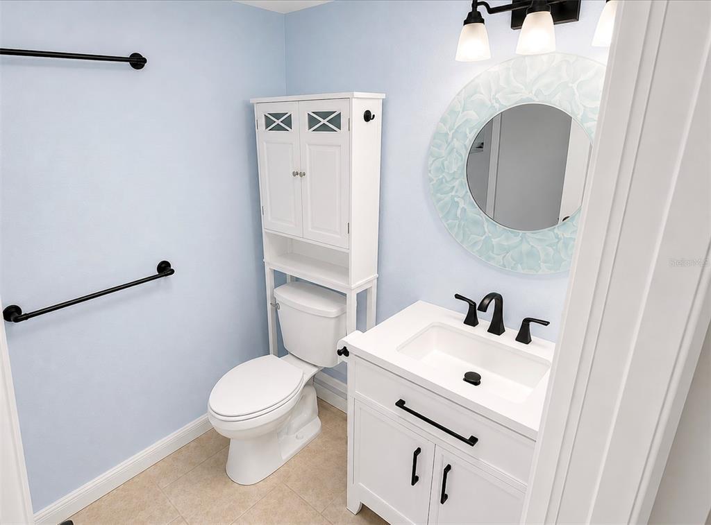 A bathroom features a white vanity, a toilet with an over-the-tank cabinet, and blue walls — 1068 LOTUS PARKWAY UNIT 815, ALTAMONTE SPRINGS, FL