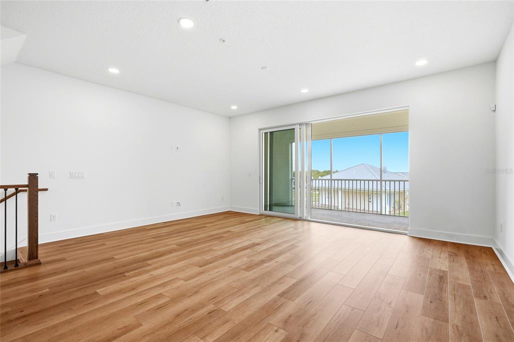 An empty room with wood-look flooring, recessed lighting, and a sliding door to a balcony — 9936 KEY HAVEN ROAD, SEMINOLE, FL