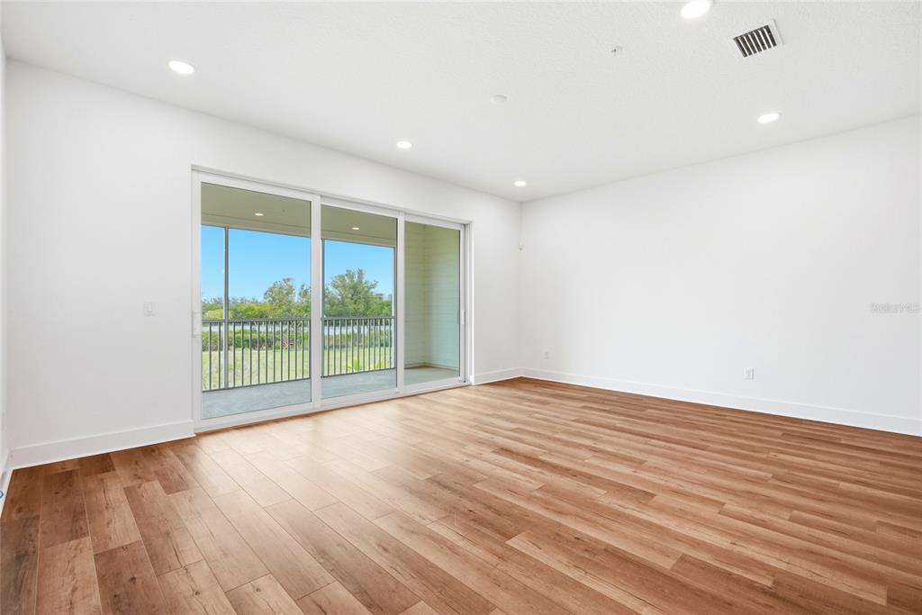 An empty room with wood-look flooring, white walls, recessed lighting, and a sliding glass door — 9936 KEY HAVEN ROAD, SEMINOLE, FL