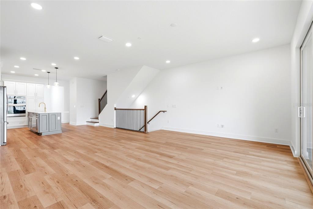 An open-concept living area features light wood flooring, a kitchen island, and a staircase — 9936 KEY HAVEN ROAD, SEMINOLE, FL