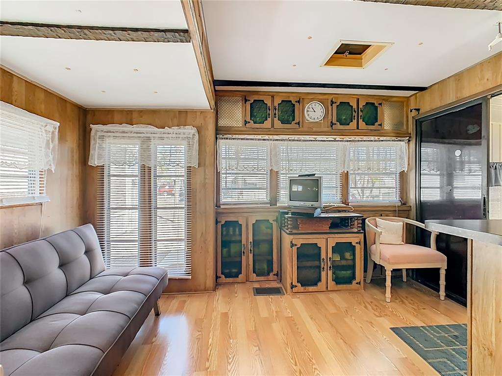 A living room features wood-paneled walls, light hardwood flooring, a gray futon, and built-in cabinetry — 9000 US HWY 192 UNIT 407, CLERMONT, FL