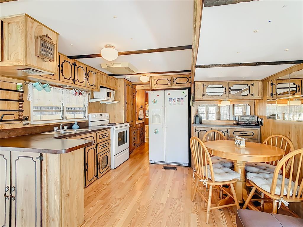 A kitchen and dining area with wood-paneled walls, light wood flooring, and wooden cabinetry — 9000 US HWY 192 UNIT 407, CLERMONT, FL
