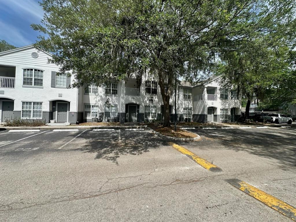 A multi-story apartment building with white siding and a parking lot in the foreground — 4332 S KIRKMAN ROAD UNIT 1004, ORLANDO, FL